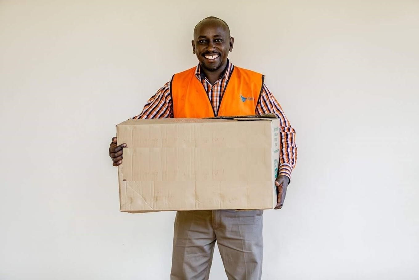 A Sam K Transporters crew member in a hi-vis vest carrying a moving box